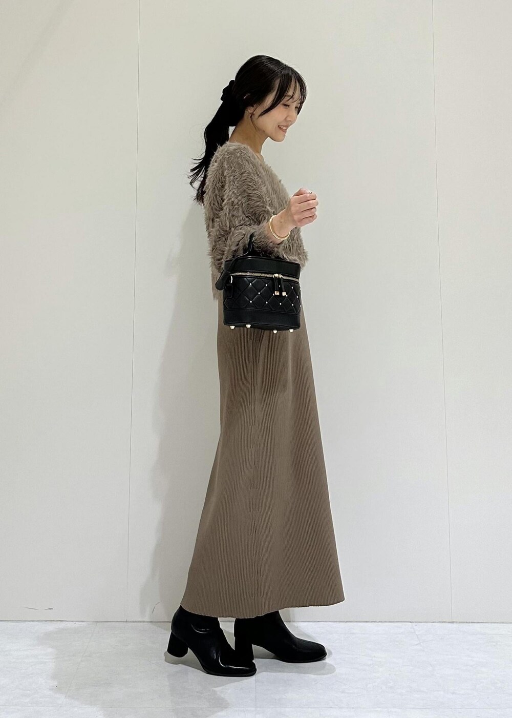 ブラック系のブーツ、ブラウン系のワンピース、ブラック系のハンドバッグを着用したレディースの秋コーディネートの3枚目の写真