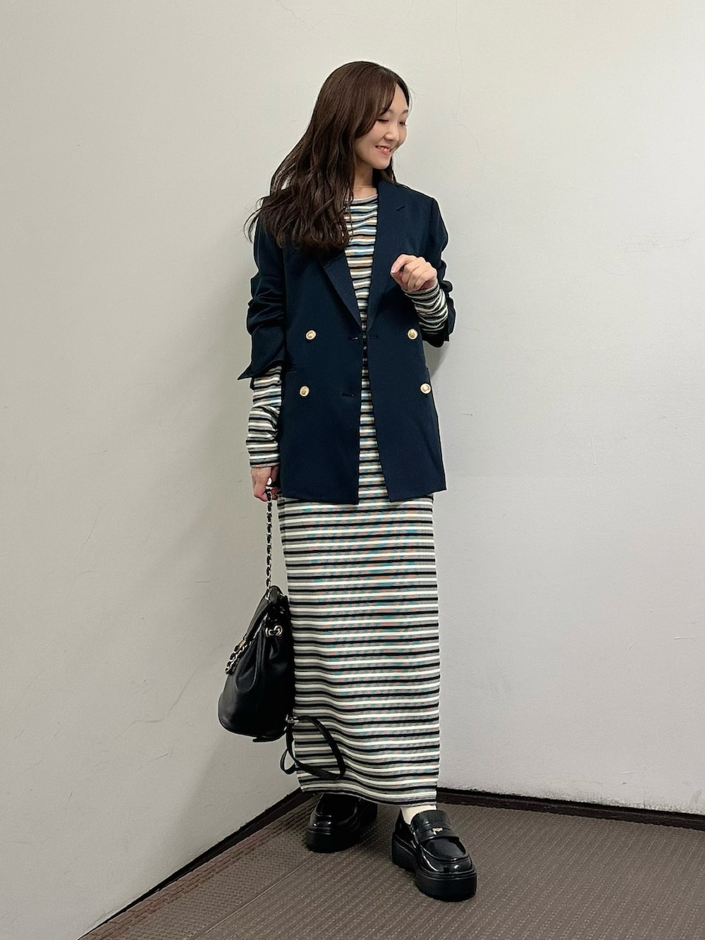 ブラック系のワンピース、ブルー系のテーラードジャケット、イエロー系のバックパック/リュックを着用したレディースの春コーディネートの2枚目の写真