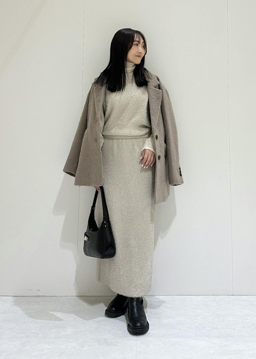 ベージュ系のスカート、ホワイト系のニット/セーター、ベージュ系のニット/セーターを着用したレディースの冬コーディネートの2枚目の写真