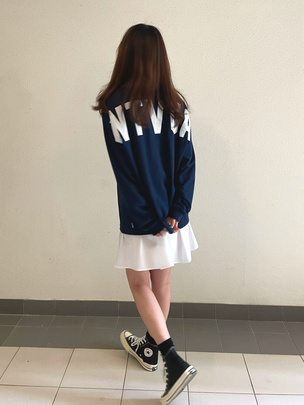 ブルー系のトップス、ホワイト系のスカート、ブラック系のスニーカーを着用したレディースの春コーディネートの2枚目の写真