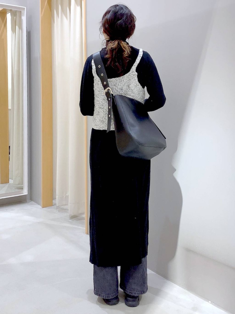 ブラック系のショルダーバッグ、グレー系のデニムパンツ、ブラック系のワンピースを着用したレディースの冬コーディネートの2枚目の写真