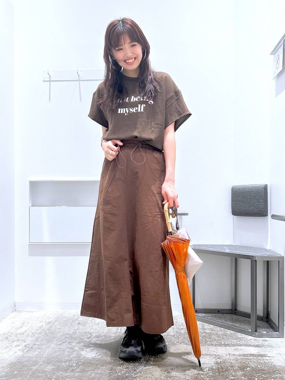 ブラウン系のスカート、ブラウン系のTシャツ/カットソー、ベージュ系のレインコート/ポンチョを着用したレディースの夏コーディネートの4枚目の写真