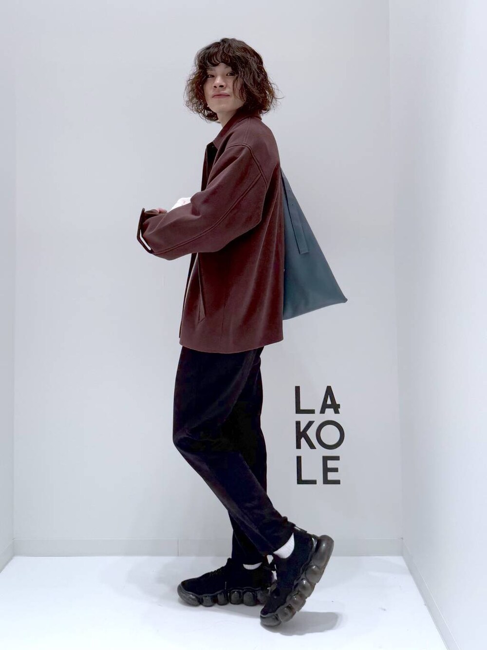 ブラウン系のブルゾン、ベージュ系のニット/セーター、ブルー系のトートバッグを着用したメンズの冬コーディネートの6枚目の写真