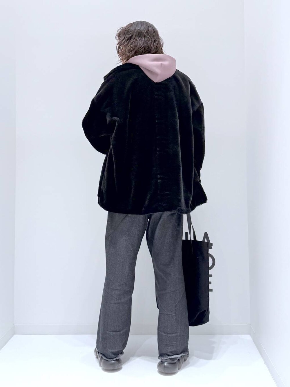 ブラック系のトートバッグ、ベージュ系のパーカー、ブラック系のデニムパンツを着用したメンズの冬コーディネートの5枚目の写真