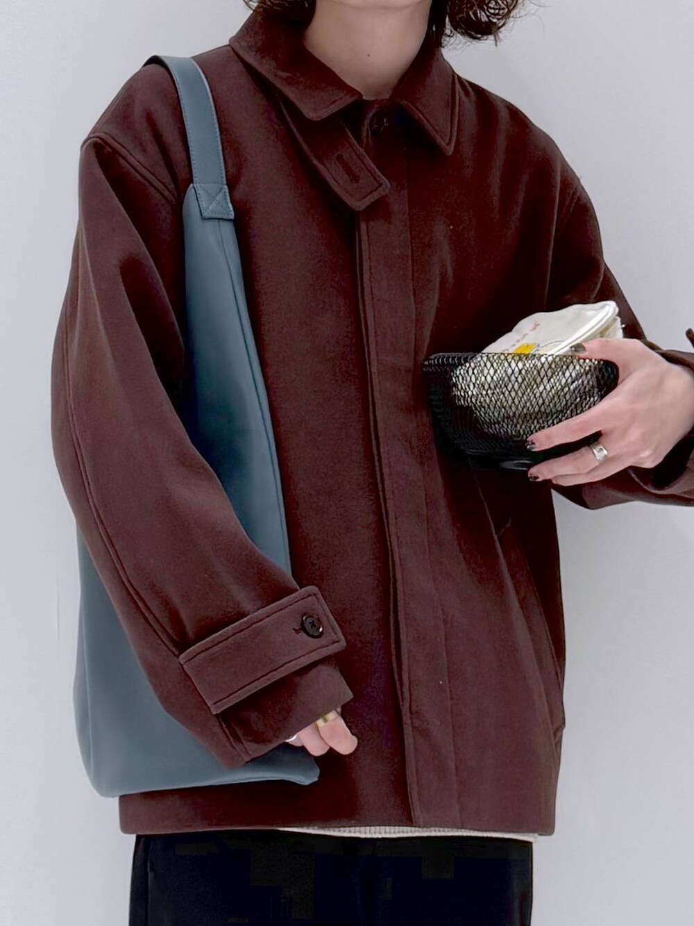 ブラウン系のブルゾン、ベージュ系のニット/セーター、ブルー系のトートバッグを着用したメンズの冬コーディネートの8枚目の写真