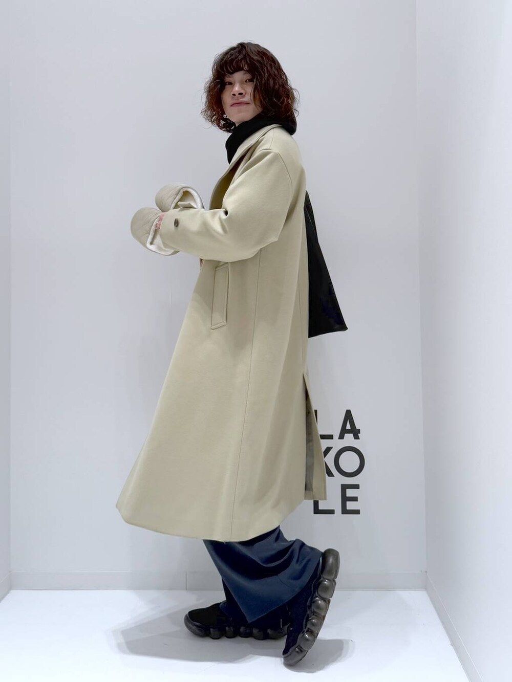 グリーン系のステンカラーコート、ブラック系のトートバッグ、ブラック系のTシャツ/カットソーを着用したメンズの冬コーディネートの5枚目の写真