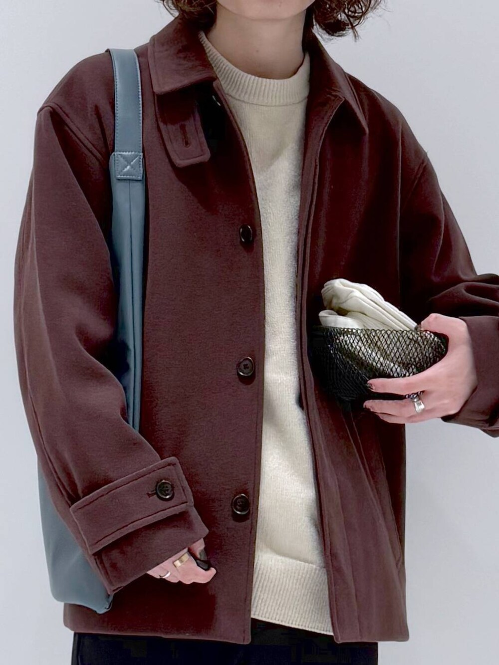 ブラウン系のブルゾン、ベージュ系のニット/セーター、ブルー系のトートバッグを着用したメンズの冬コーディネートの7枚目の写真