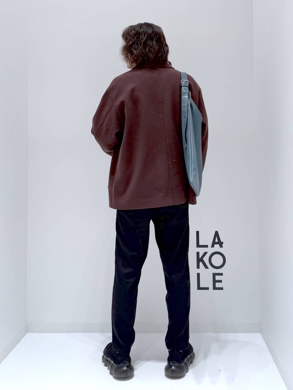 ブラウン系のブルゾン、ベージュ系のニット/セーター、ブルー系のトートバッグを着用したメンズの冬コーディネートの5枚目の写真