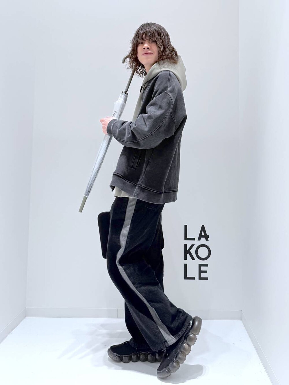 グリーン系のパーカー、グレー系のブルゾン、ブラック系のデニムパンツを着用したメンズの春コーディネートの5枚目の写真