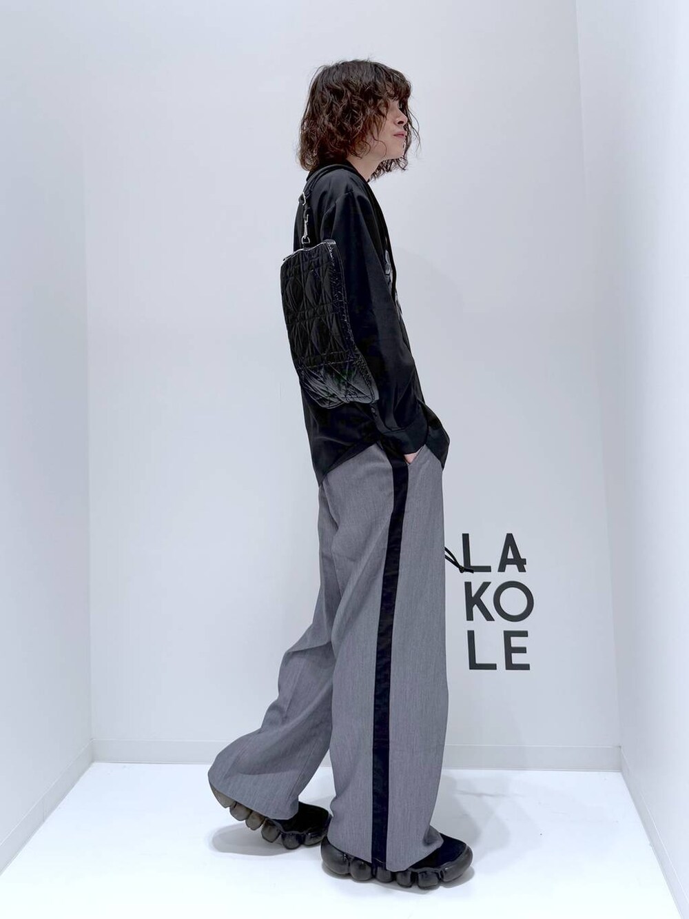 グレー系のスラックス、ブラック系のショルダーバッグ、ブラック系のシャツ/ブラウスを着用したメンズの冬コーディネートの2枚目の写真