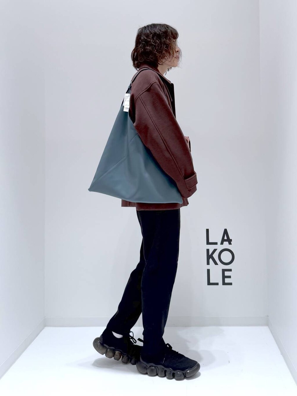 ブラウン系のブルゾン、ベージュ系のニット/セーター、ブルー系のトートバッグを着用したメンズの冬コーディネートの4枚目の写真