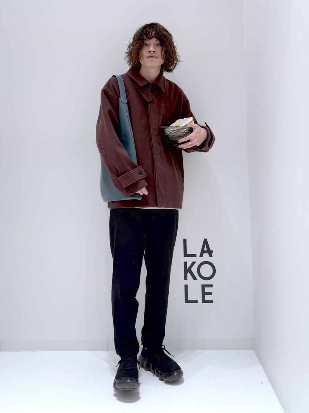 ブラウン系のブルゾン、ベージュ系のニット/セーター、ブルー系のトートバッグを着用したメンズの冬コーディネートの3枚目の写真