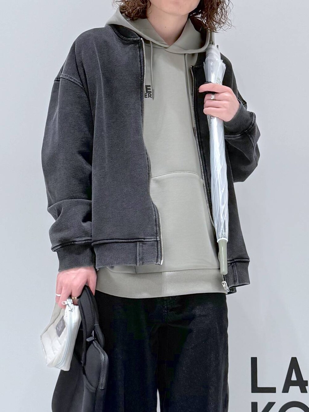 グリーン系のパーカー、グレー系のブルゾン、ブラック系のデニムパンツを着用したメンズの春コーディネートの6枚目の写真