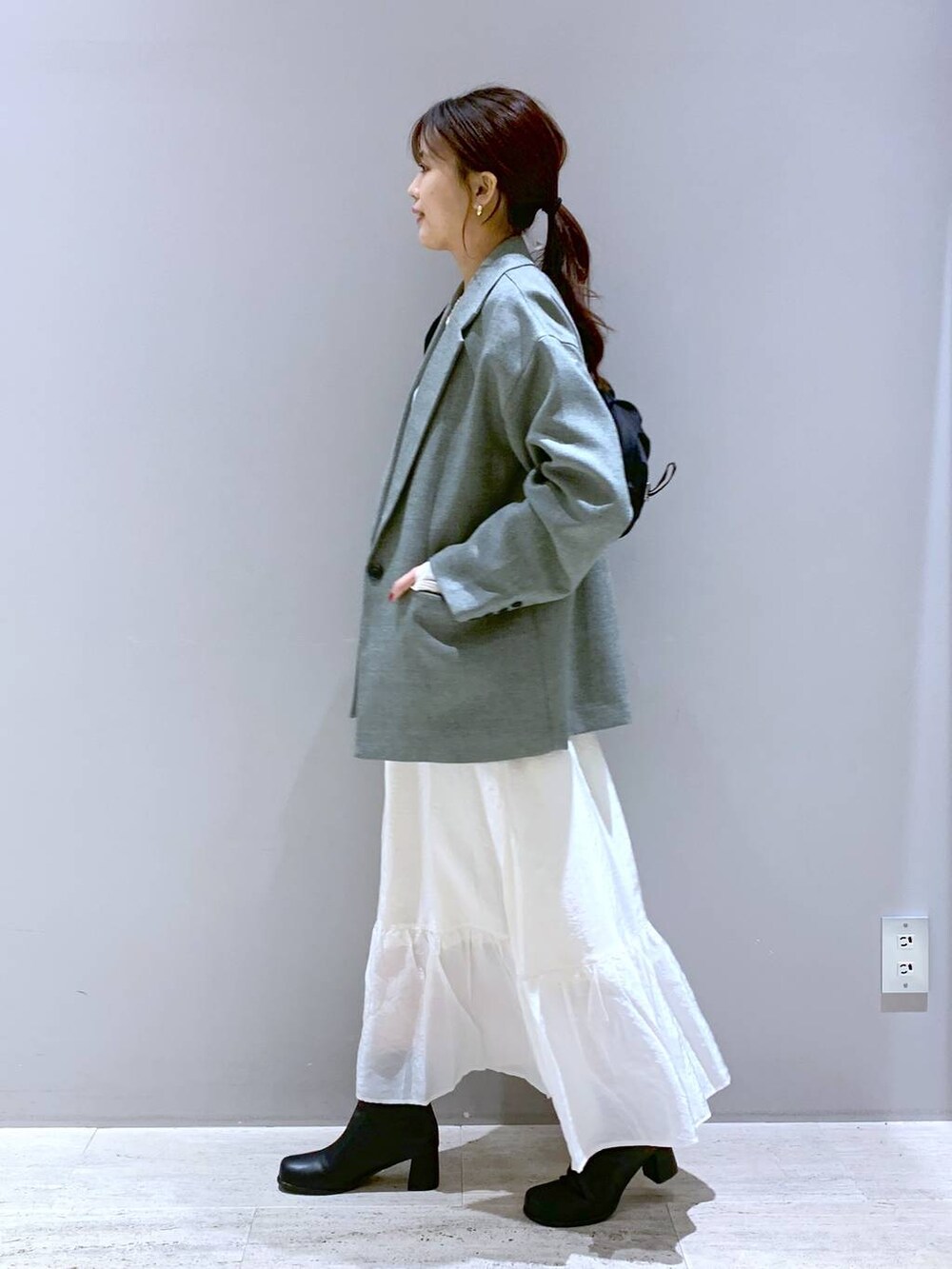 ホワイト系のスカート、ブラック系のブーツ、ブラック系のショルダーバッグを着用したレディースの春コーディネートの2枚目の写真