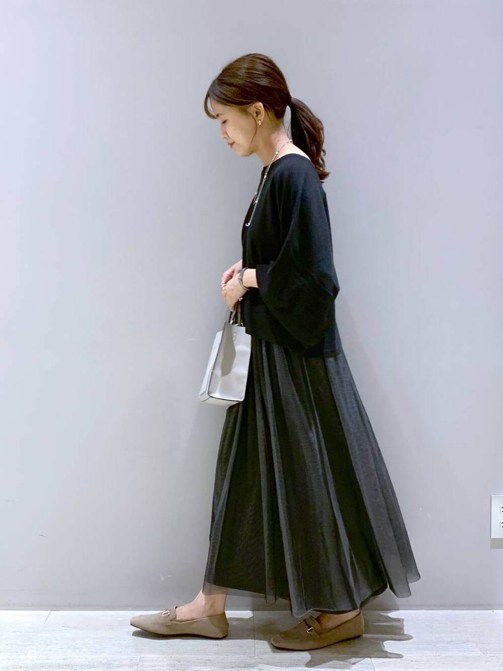 ブラック系のニット/セーター、ベージュ系のローファー、ベージュ系のショルダーバッグを着用したレディースの秋コーディネートの2枚目の写真