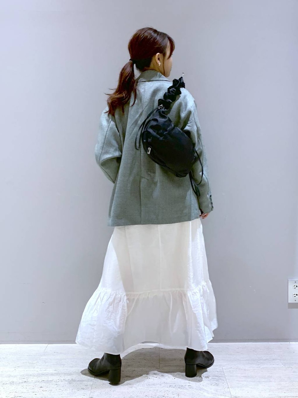 ホワイト系のスカート、ブラック系のブーツ、ブラック系のショルダーバッグを着用したレディースの春コーディネートの3枚目の写真