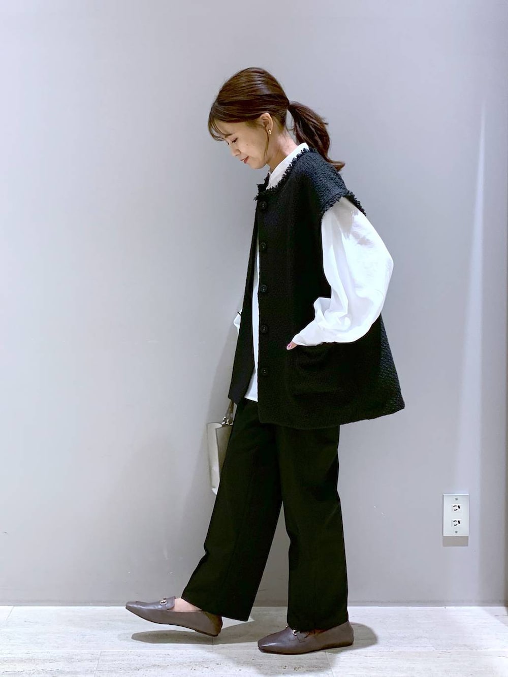 ブラック系のその他パンツ、ブラウン系のローファー、ベージュ系のショルダーバッグを着用したレディースの秋コーディネートの2枚目の写真