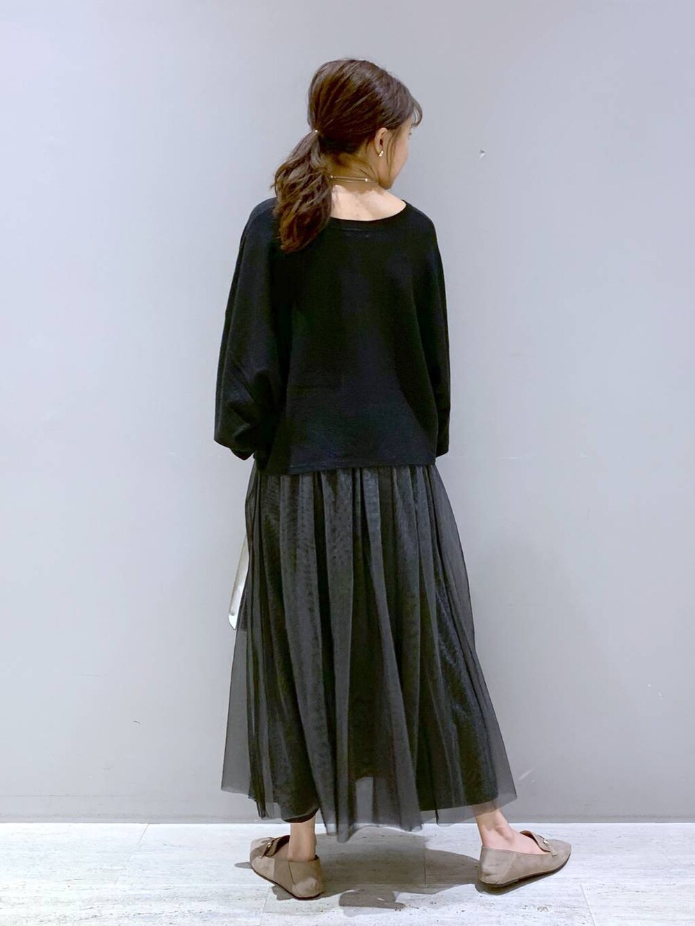 ブラック系のニット/セーター、ベージュ系のローファー、ベージュ系のショルダーバッグを着用したレディースの秋コーディネートの3枚目の写真