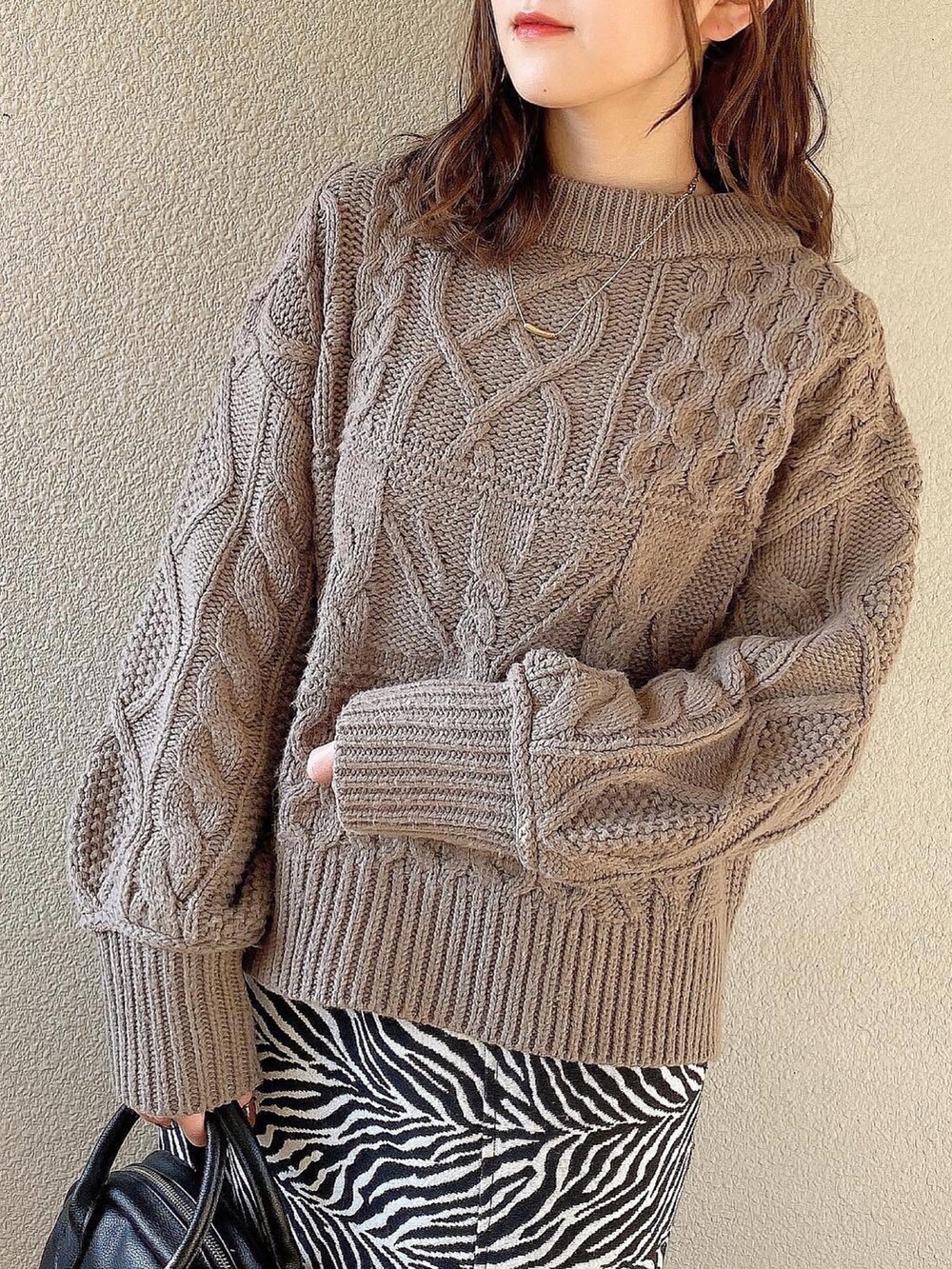 ブラウン系のトップス、ブラック系のスカート、ブラック系のブーツを着用したレディースの冬コーディネートの2枚目の写真