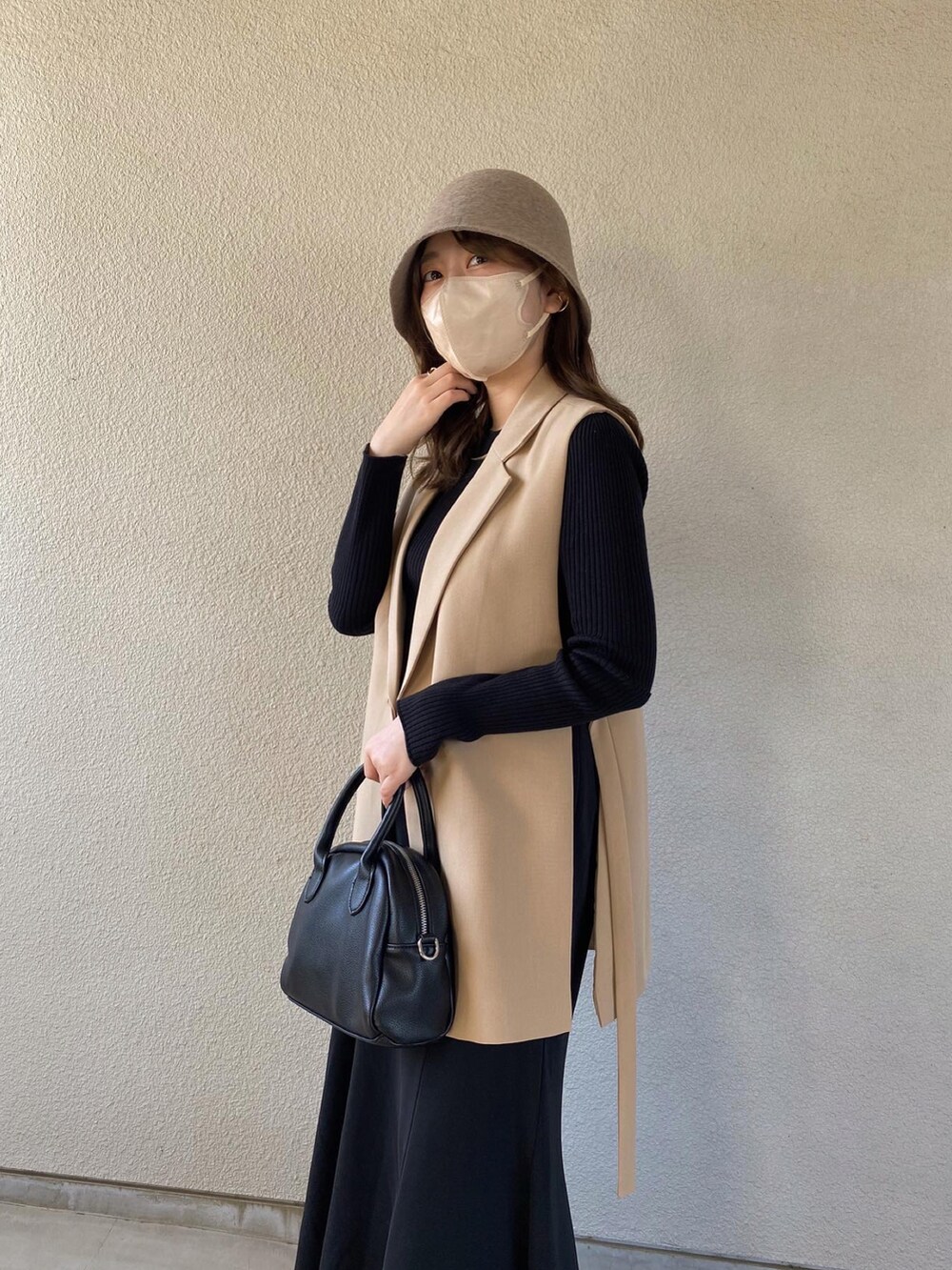 ベージュ系のベスト、ブラック系のトップス、ブラック系のスカートを着用したレディースの春コーディネートの3枚目の写真