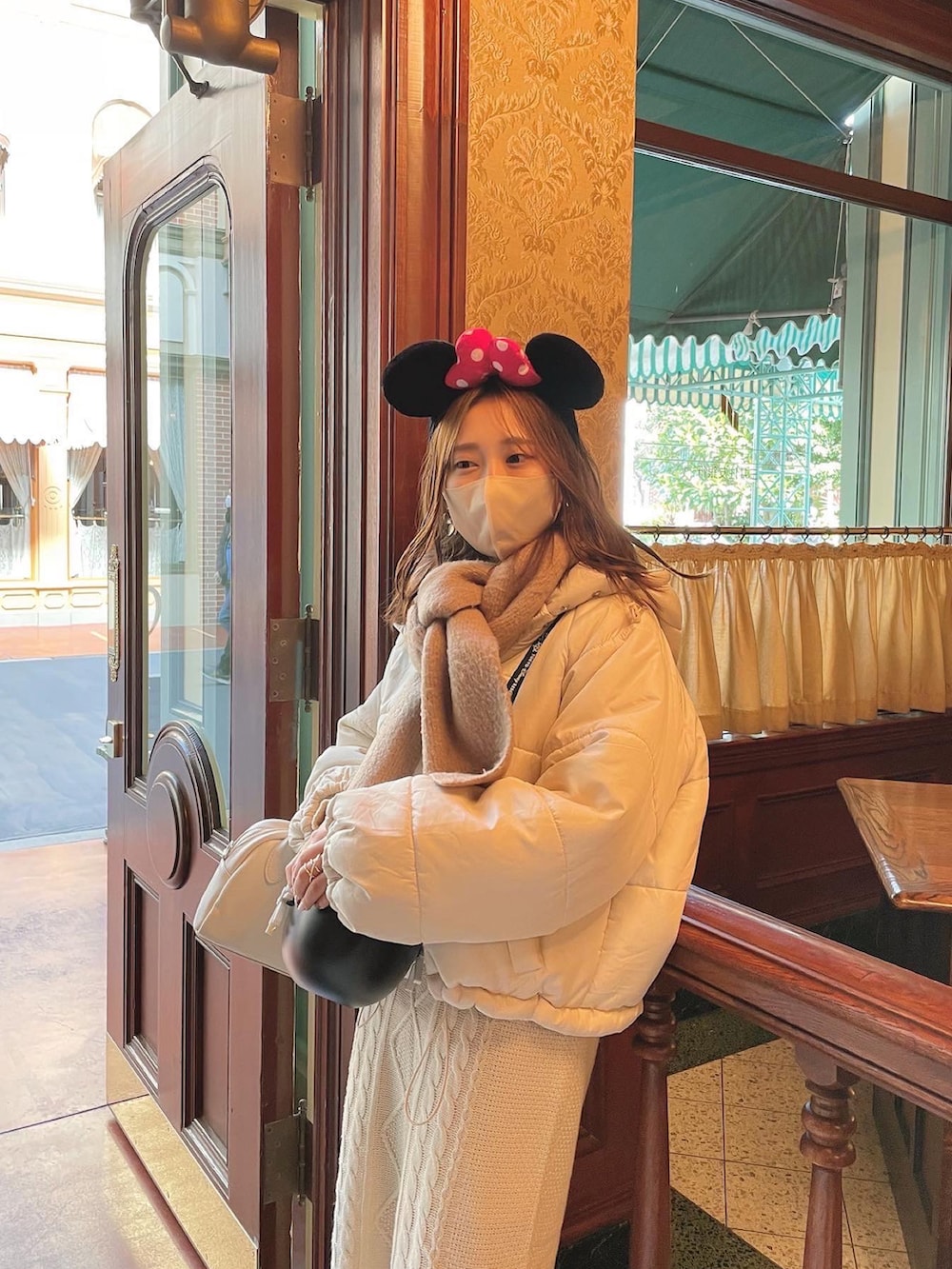 ベージュ系のセットアップ、ホワイト系のボストンバッグ、ホワイト系のブーツを着用したレディースの冬コーディネートの2枚目の写真