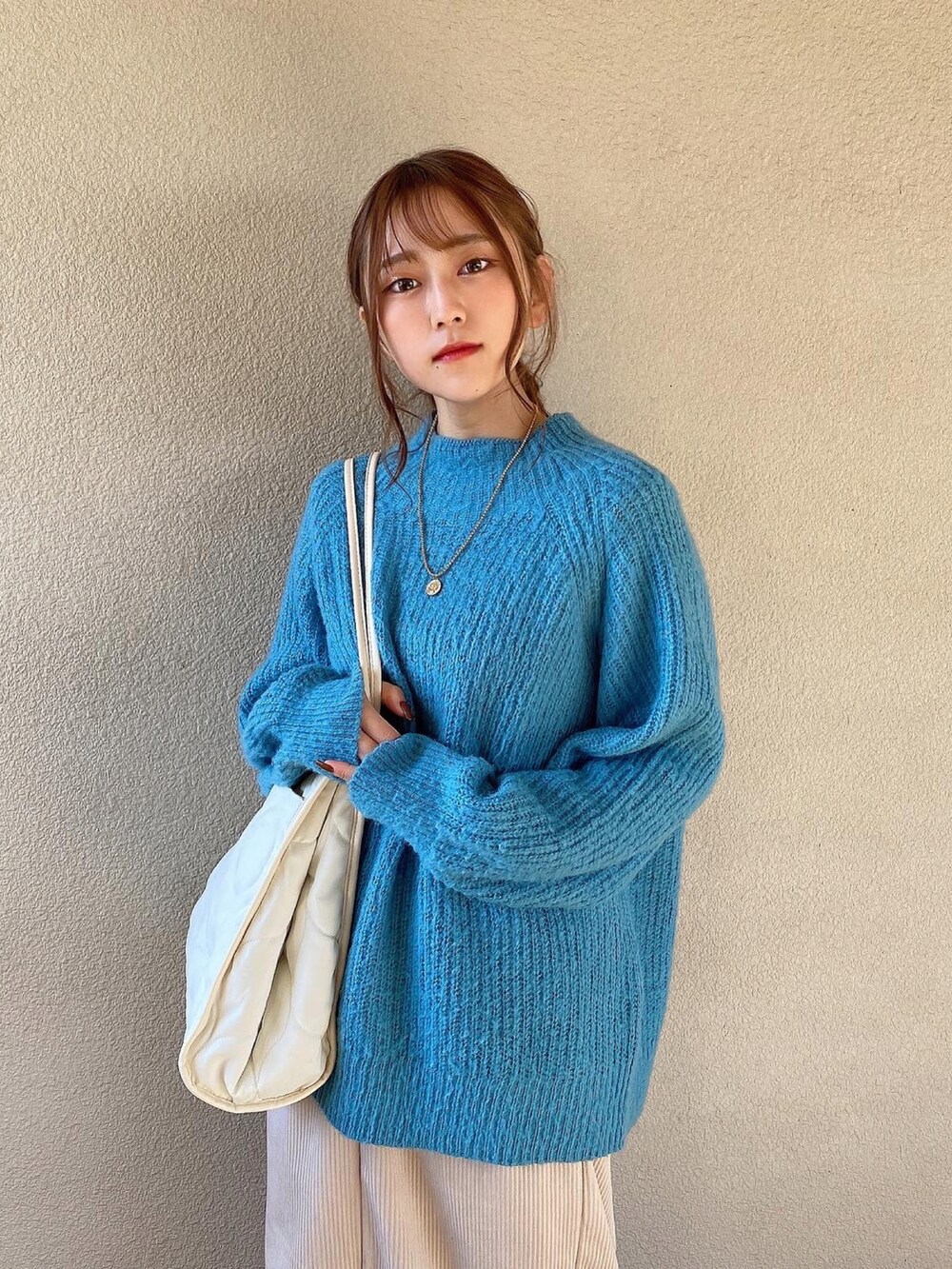 ブルー系のニット/セーター、ホワイト系のスカート、ホワイト系のトートバッグを着用したレディースの冬コーディネートの3枚目の写真