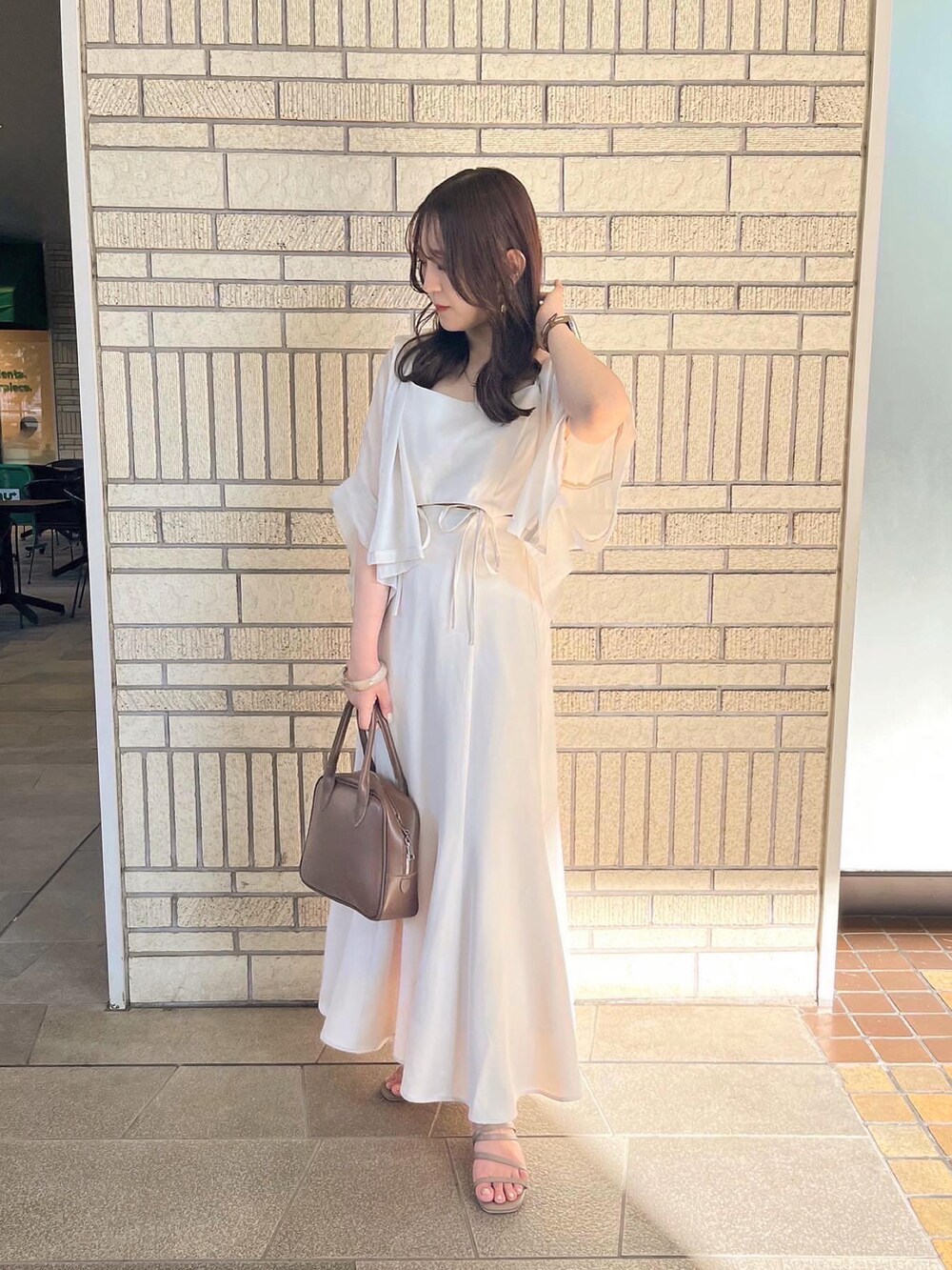 ホワイト系のワンピース、ブラウン系のボストンバッグ、ベージュ系のサンダルを着用したレディースの夏コーディネートの2枚目の写真