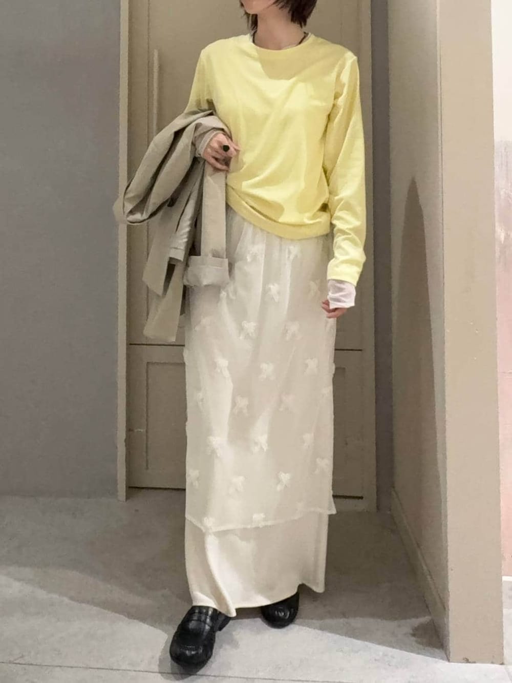 ホワイト系のスカート、ブラック系のローファー、ベージュ系のその他アウターを着用したレディースの春コーディネートの3枚目の写真