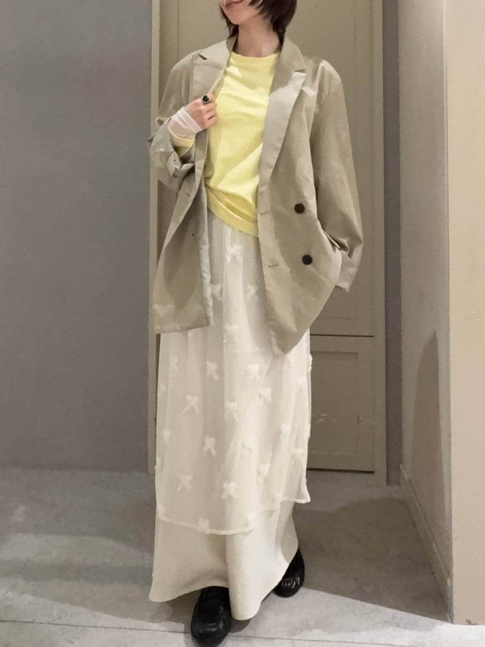 ホワイト系のスカート、ブラック系のローファー、ベージュ系のその他アウターを着用したレディースの春コーディネートの2枚目の写真