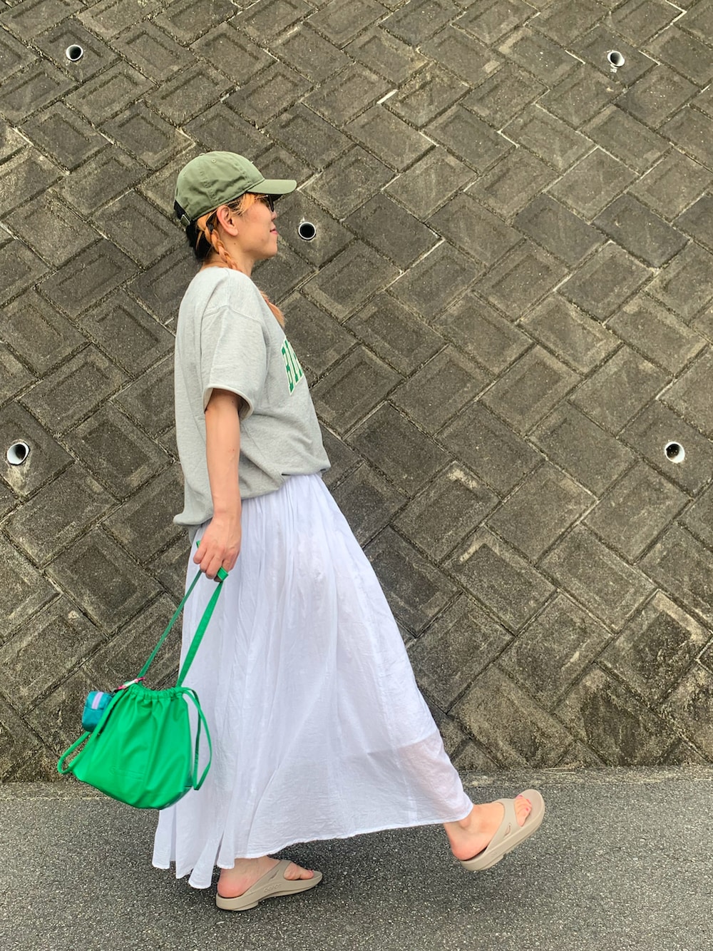 グレー系のTシャツ/カットソー、ホワイト系のスカート、ベージュ系のサンダルを着用したレディースの秋コーディネートの4枚目の写真