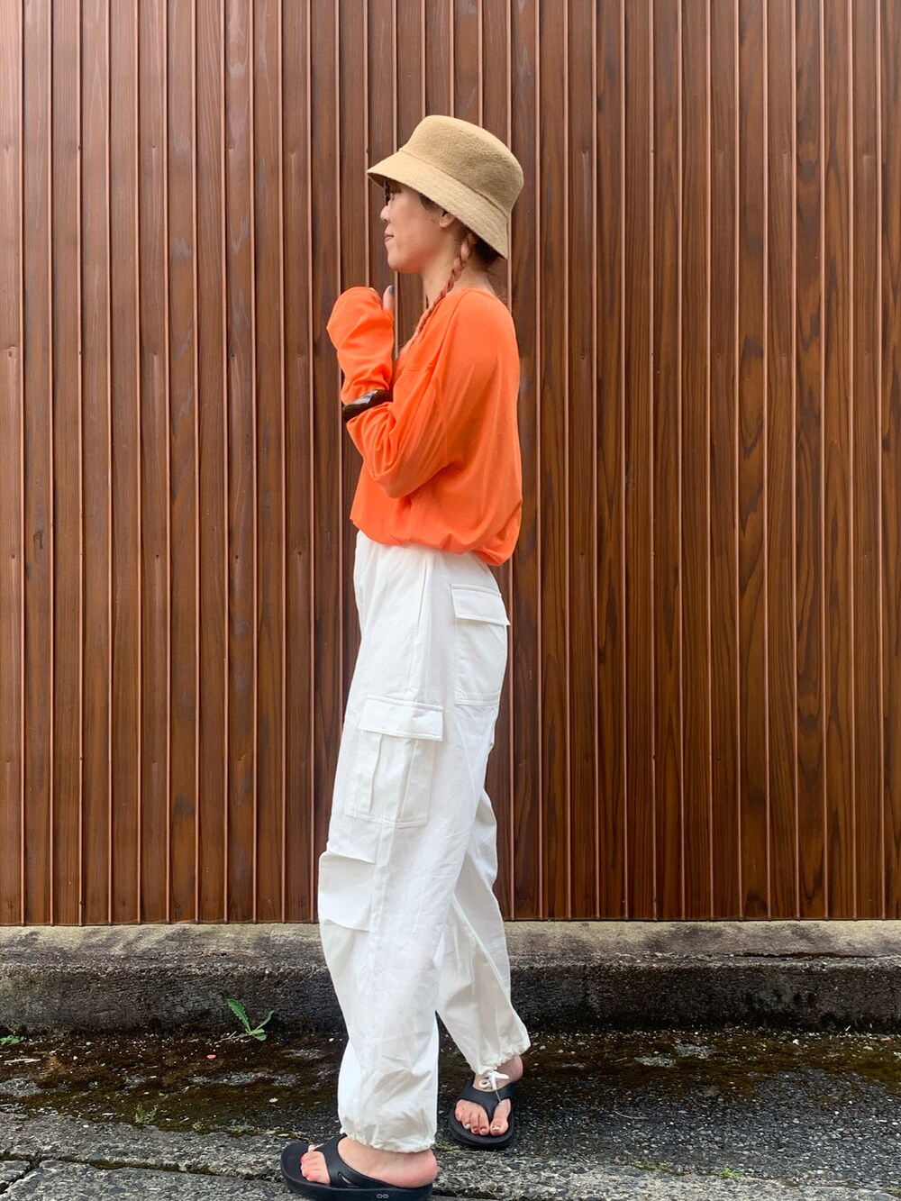 オレンジ系のTシャツ/カットソー、ホワイト系のカーゴパンツ、ブラック系のサンダルを着用したレディースの夏コーディネートの2枚目の写真