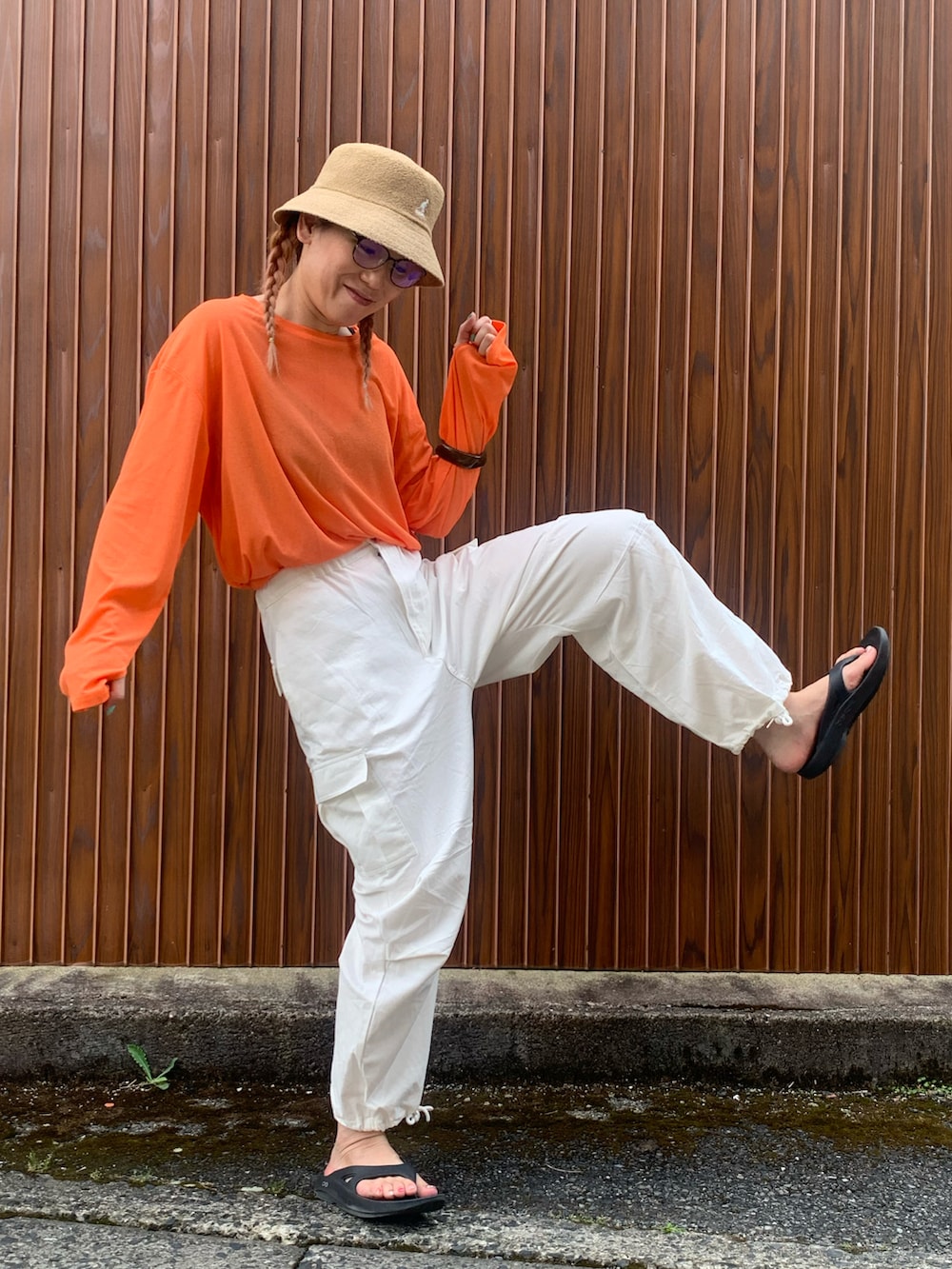 オレンジ系のTシャツ/カットソー、ホワイト系のカーゴパンツ、ブラック系のサンダルを着用したレディースの夏コーディネートの4枚目の写真