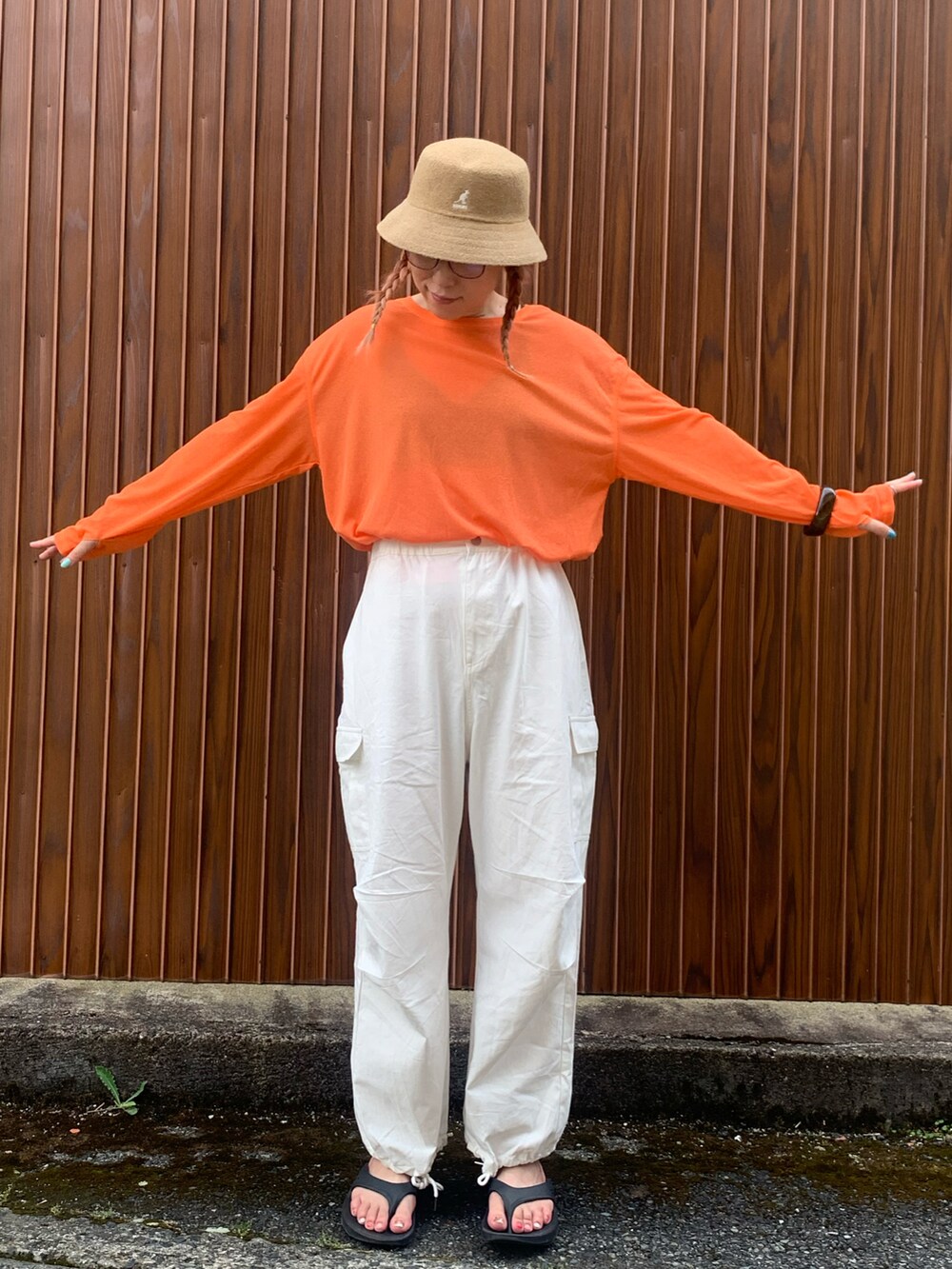 オレンジ系のTシャツ/カットソー、ホワイト系のカーゴパンツ、ブラック系のサンダルを着用したレディースの夏コーディネートの3枚目の写真