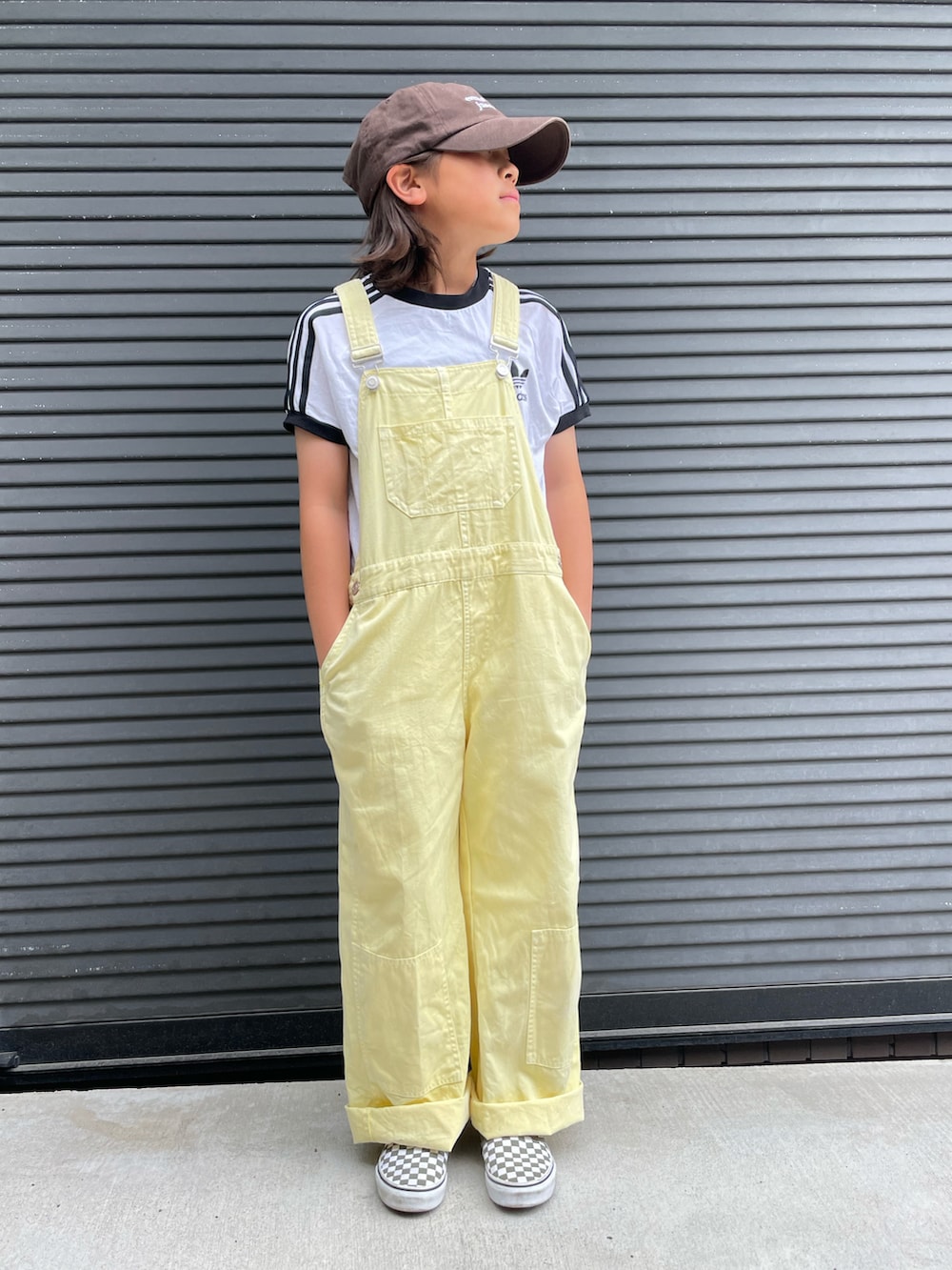 イエロー系のサロペット/オーバーオール、ホワイト系のTシャツ/カットソー、グリーン系のスニーカーを着用したキッズの春コーディネートの2枚目の写真