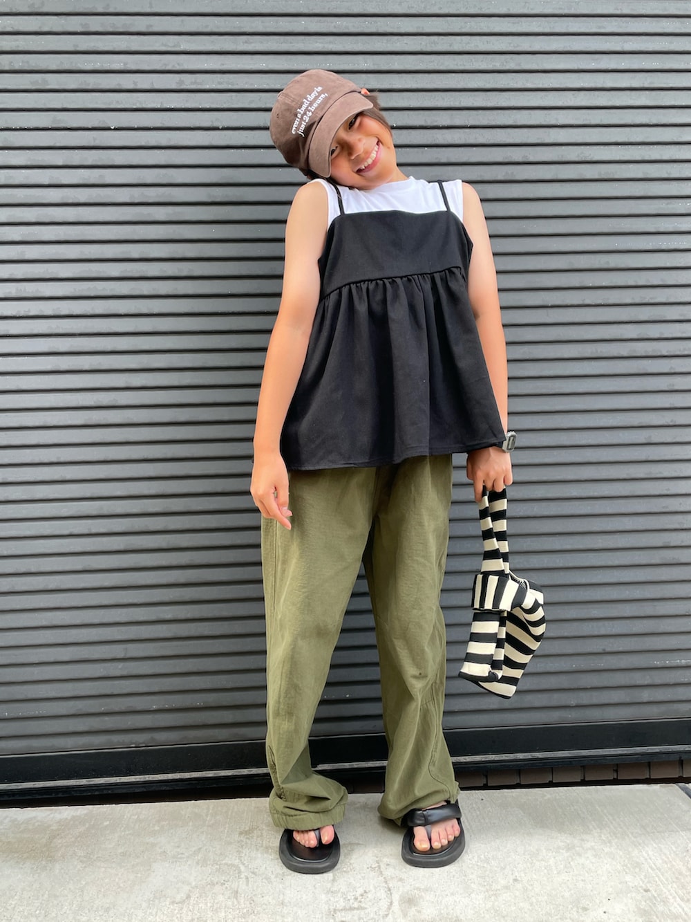 ブラック系のキャミソール、グリーン系のカーゴパンツ、ホワイト系のタンクトップを着用したキッズの夏コーディネートの5枚目の写真