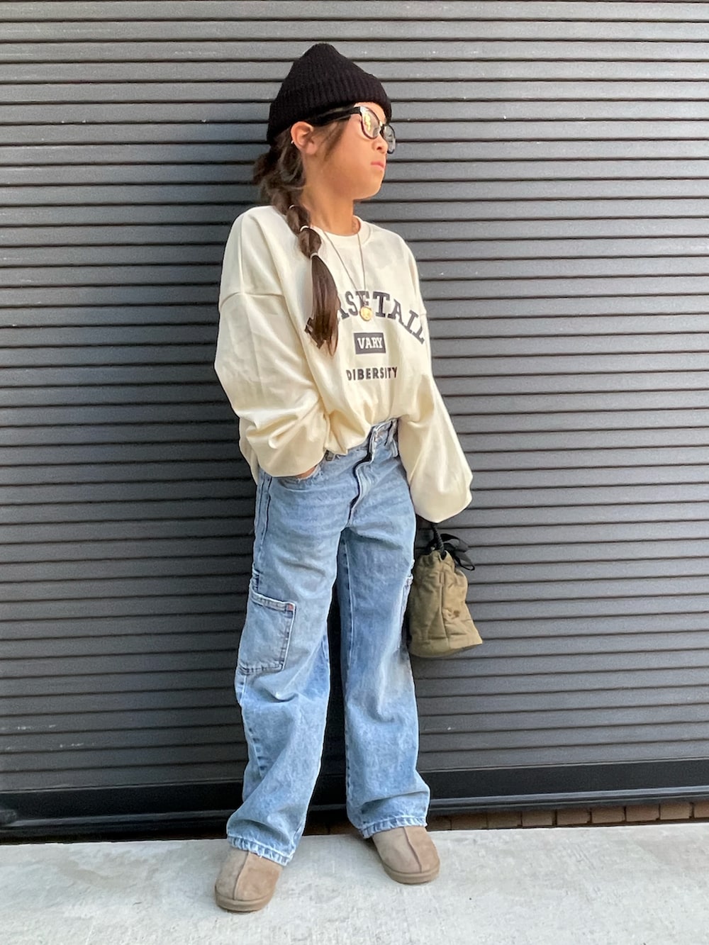 ホワイト系のスウェット、ブルー系のデニムパンツ、グリーン系のショルダーバッグを着用したキッズの秋コーディネートの3枚目の写真