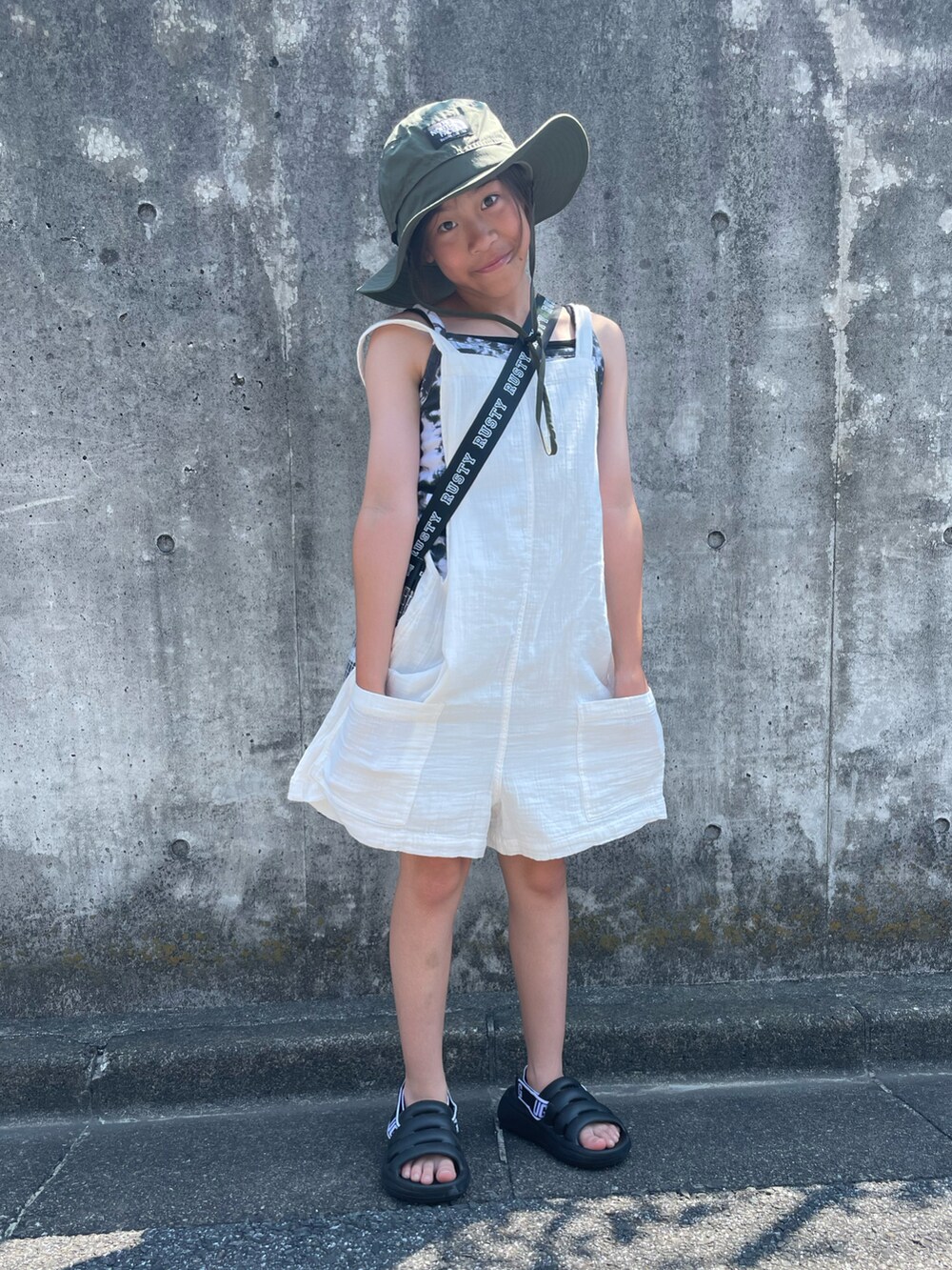 ホワイト系のサロペット/オーバーオール、ブラック系のキャミソール、ブラック系のトートバッグを着用したキッズの夏コーディネートの4枚目の写真