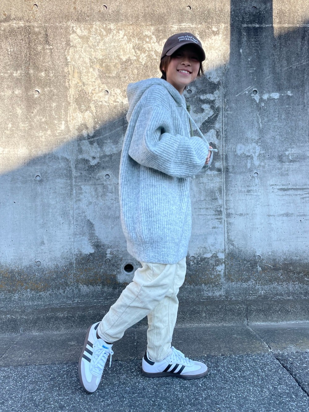 グレー系のニット/セーター、ホワイト系のその他パンツ、グリーン系のショルダーバッグを着用したキッズの冬コーディネートの5枚目の写真