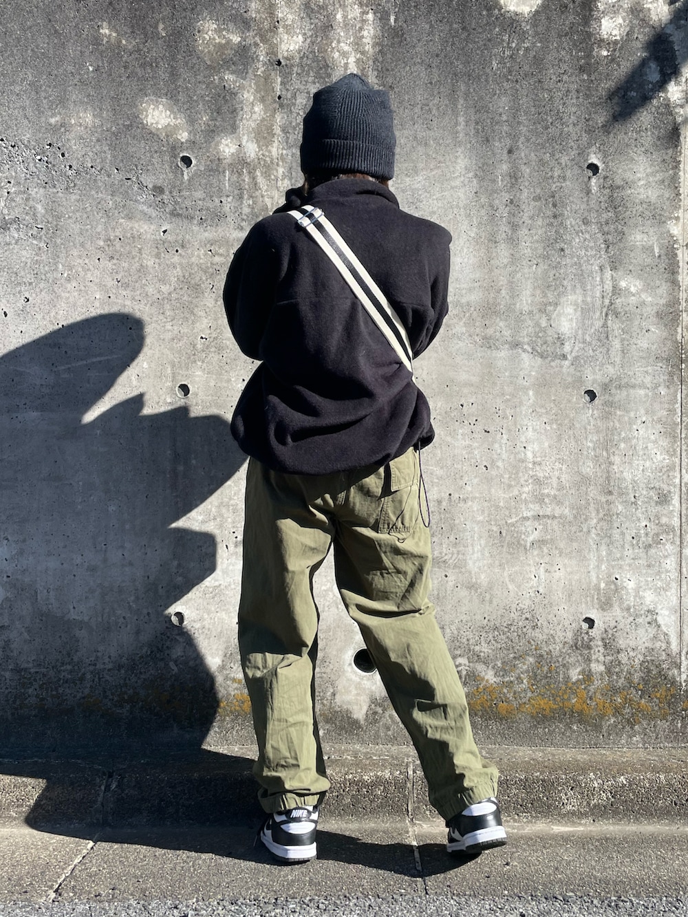 ブラック系のショルダーバッグ、ブラック系のトップス、グリーン系のカーゴパンツを着用したキッズの秋コーディネートの3枚目の写真