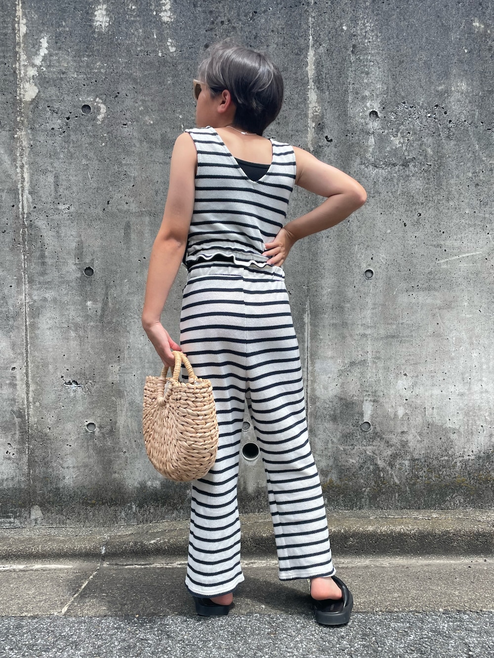 ホワイト系のアンサンブル、ベージュ系のかごバッグ、ブラック系のサンダルを着用したキッズの夏コーディネートの3枚目の写真