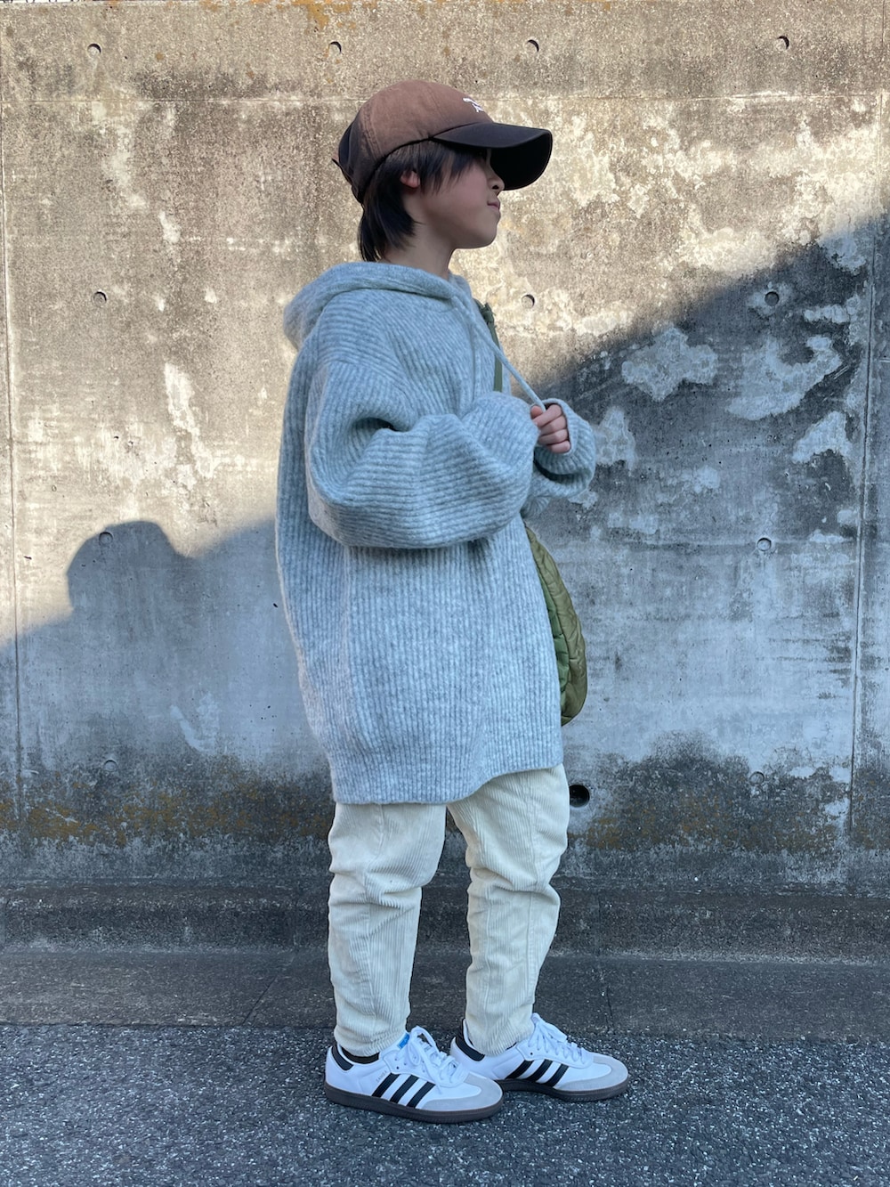 グレー系のニット/セーター、ホワイト系のその他パンツ、グリーン系のショルダーバッグを着用したキッズの冬コーディネートの2枚目の写真