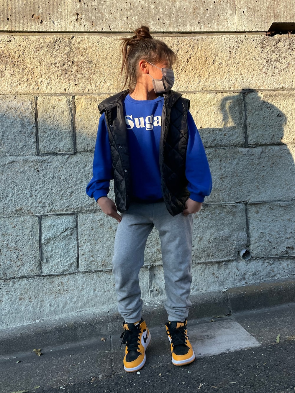 ブラック系のダウンベスト、ブルー系のスウェット、グレー系のその他パンツを着用したキッズの冬コーディネートの2枚目の写真