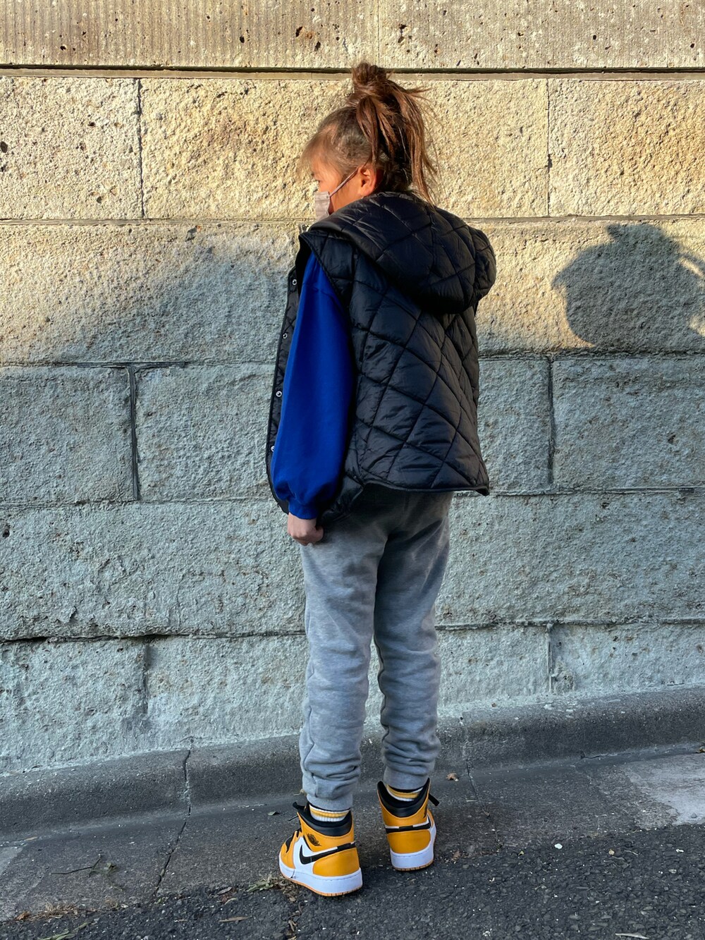 ブラック系のダウンベスト、ブルー系のスウェット、グレー系のその他パンツを着用したキッズの冬コーディネートの3枚目の写真