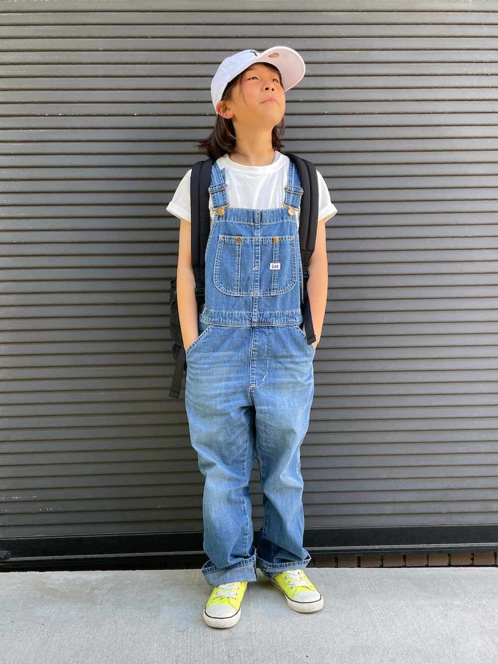 ブルー系のサロペット/オーバーオール、ブラック系のバックパック/リュック、ホワイト系のTシャツ/カットソーを着用したキッズの春コーディネートの4枚目の写真