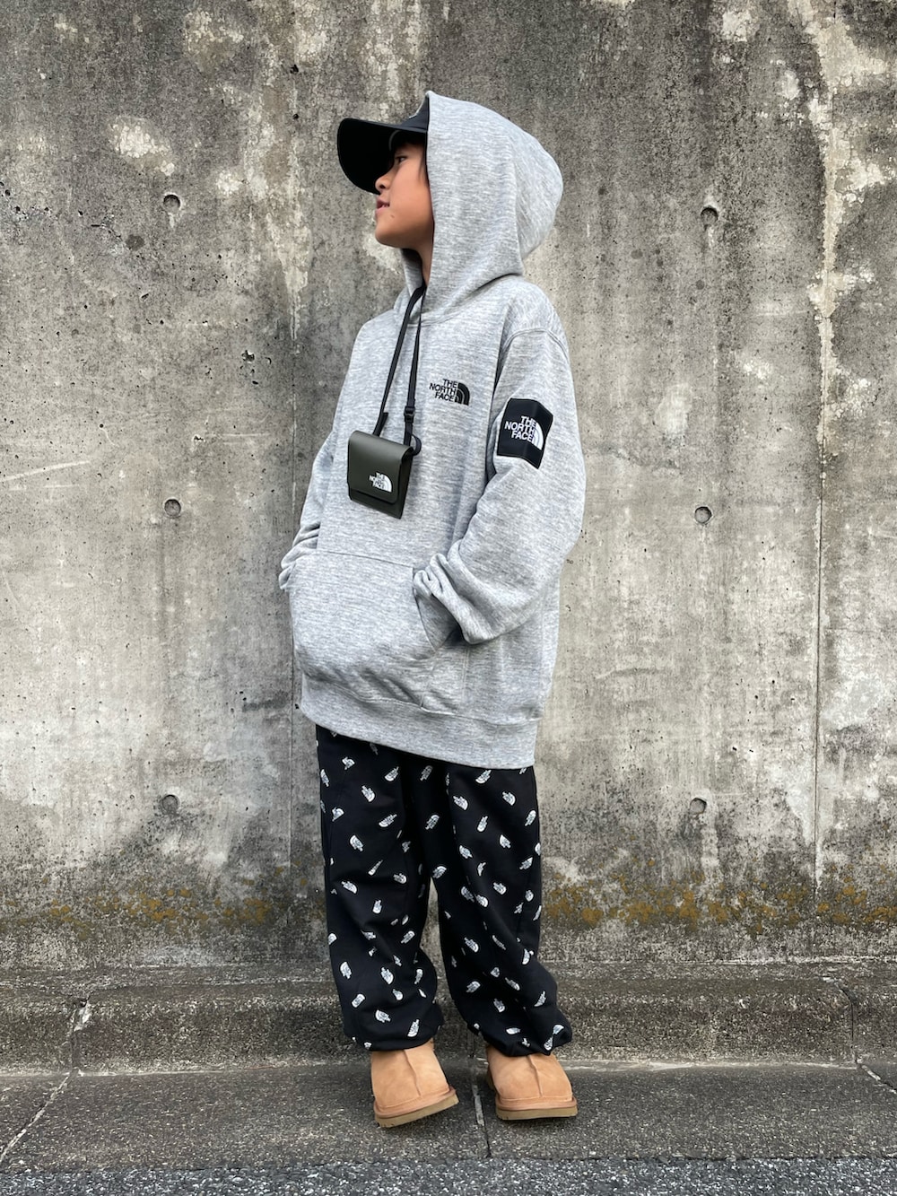 グレー系のパーカー、ブラック系のスウェットパンツ、グリーン系のショルダーバッグを着用したキッズの冬コーディネートの5枚目の写真