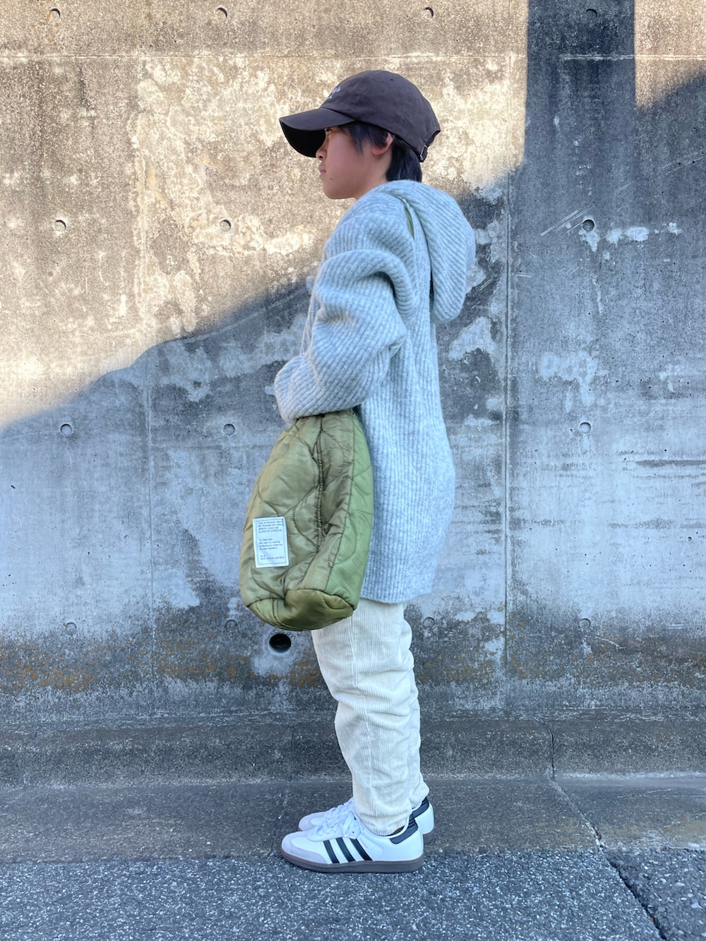 グレー系のニット/セーター、ホワイト系のその他パンツ、グリーン系のショルダーバッグを着用したキッズの冬コーディネートの4枚目の写真