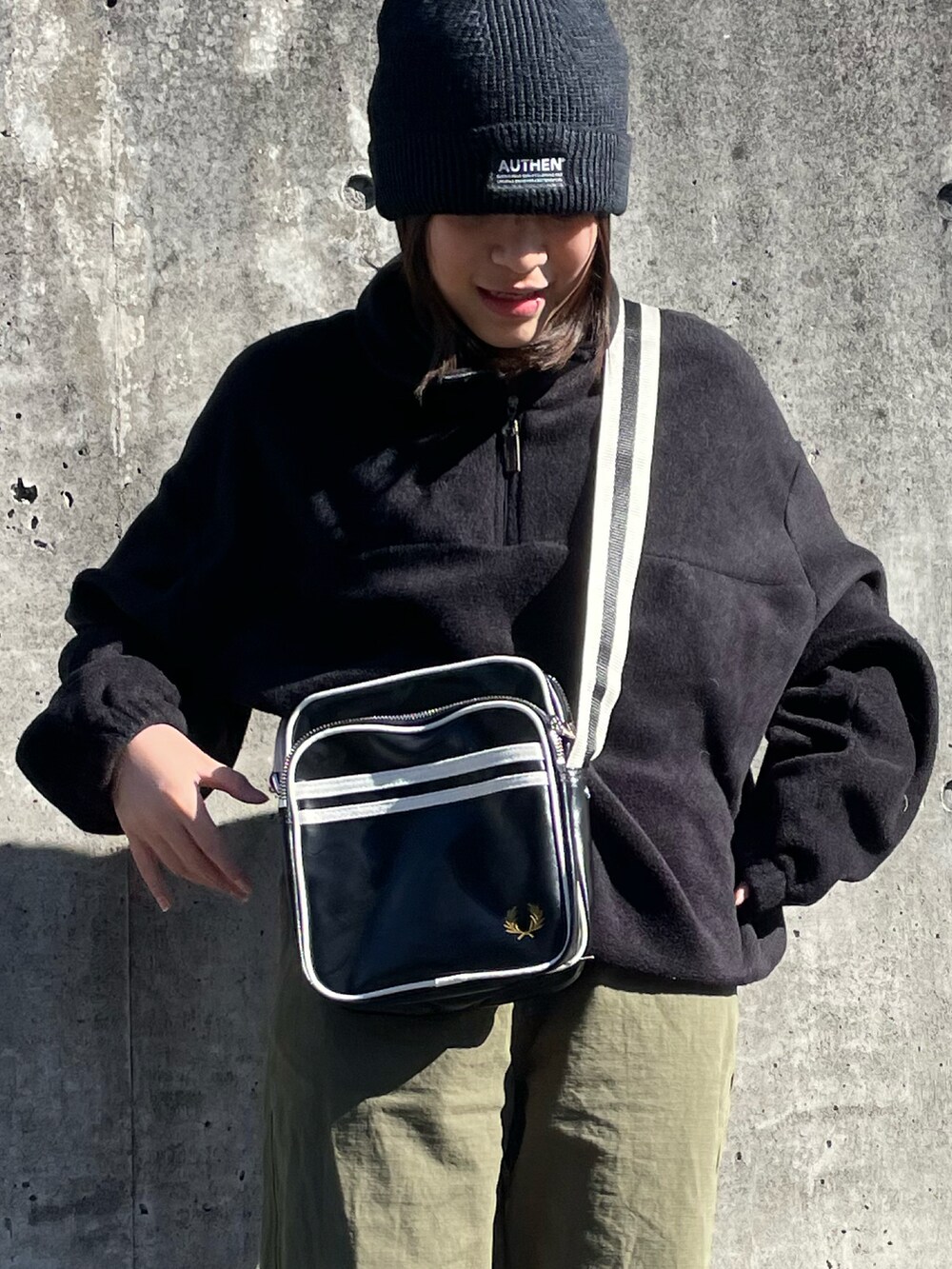 ブラック系のショルダーバッグ、ブラック系のトップス、グリーン系のカーゴパンツを着用したキッズの秋コーディネートの5枚目の写真