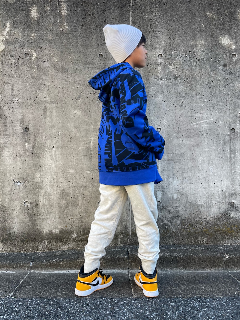 ブルー系のパーカー、ベージュ系のスウェットパンツ、オレンジ系のスニーカーを着用したキッズの秋コーディネートの4枚目の写真