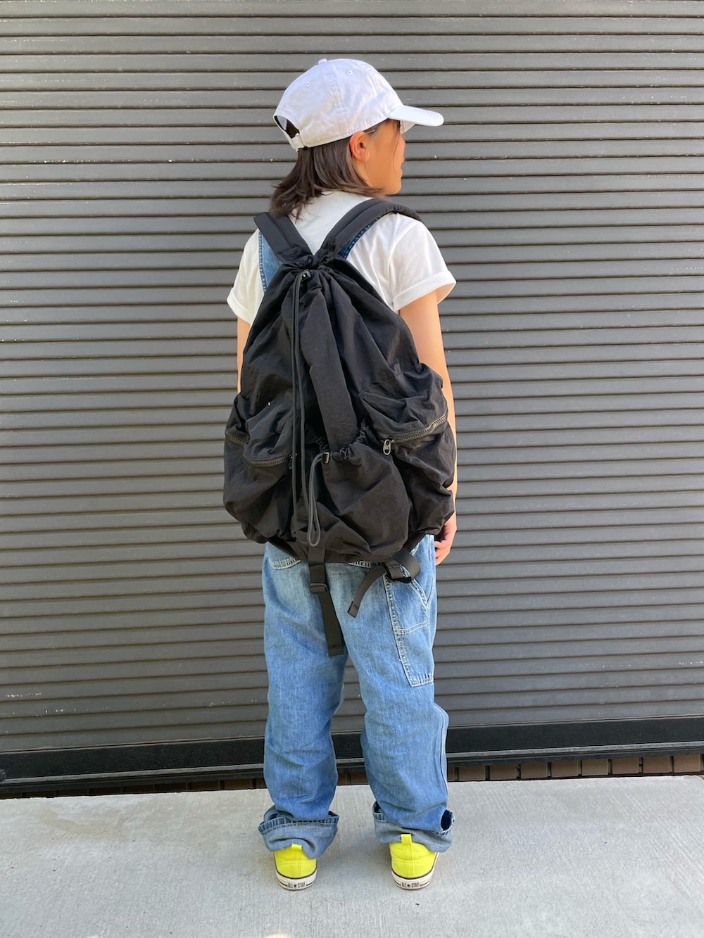 ブルー系のサロペット/オーバーオール、ブラック系のバックパック/リュック、ホワイト系のTシャツ/カットソーを着用したキッズの春コーディネートの2枚目の写真
