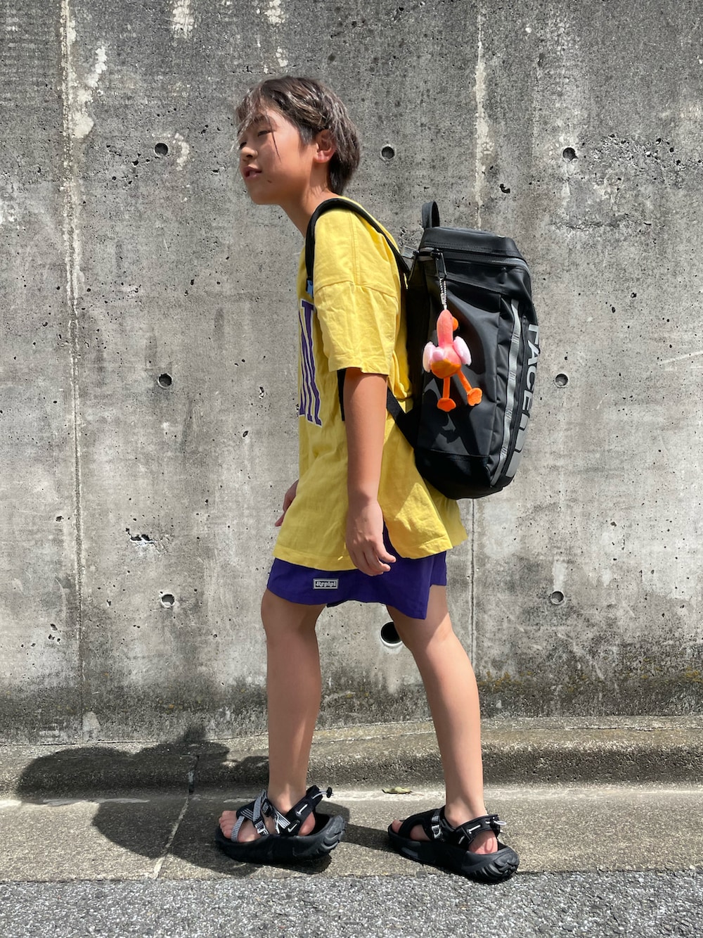 イエロー系のTシャツ/カットソー、パープル系のその他パンツ、ブラック系のバックパック/リュックを着用したキッズの夏コーディネートの2枚目の写真
